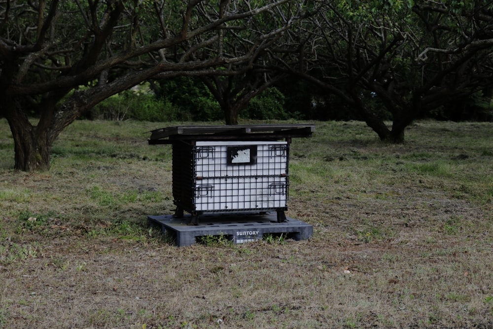 a beehive in a field with trees in the background