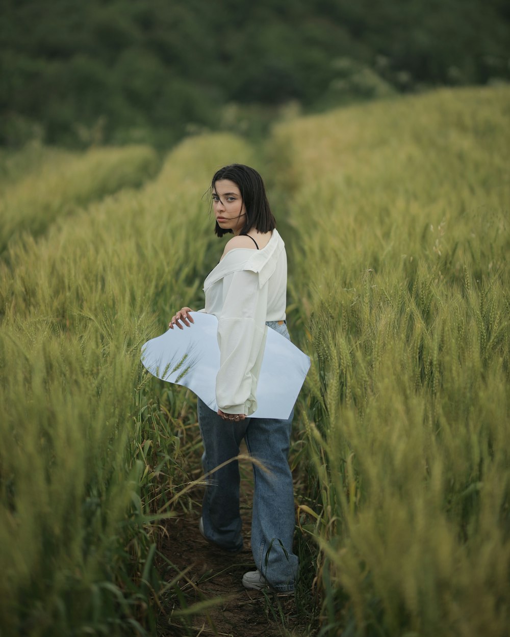 a woman standing in a field holding a piece of paper