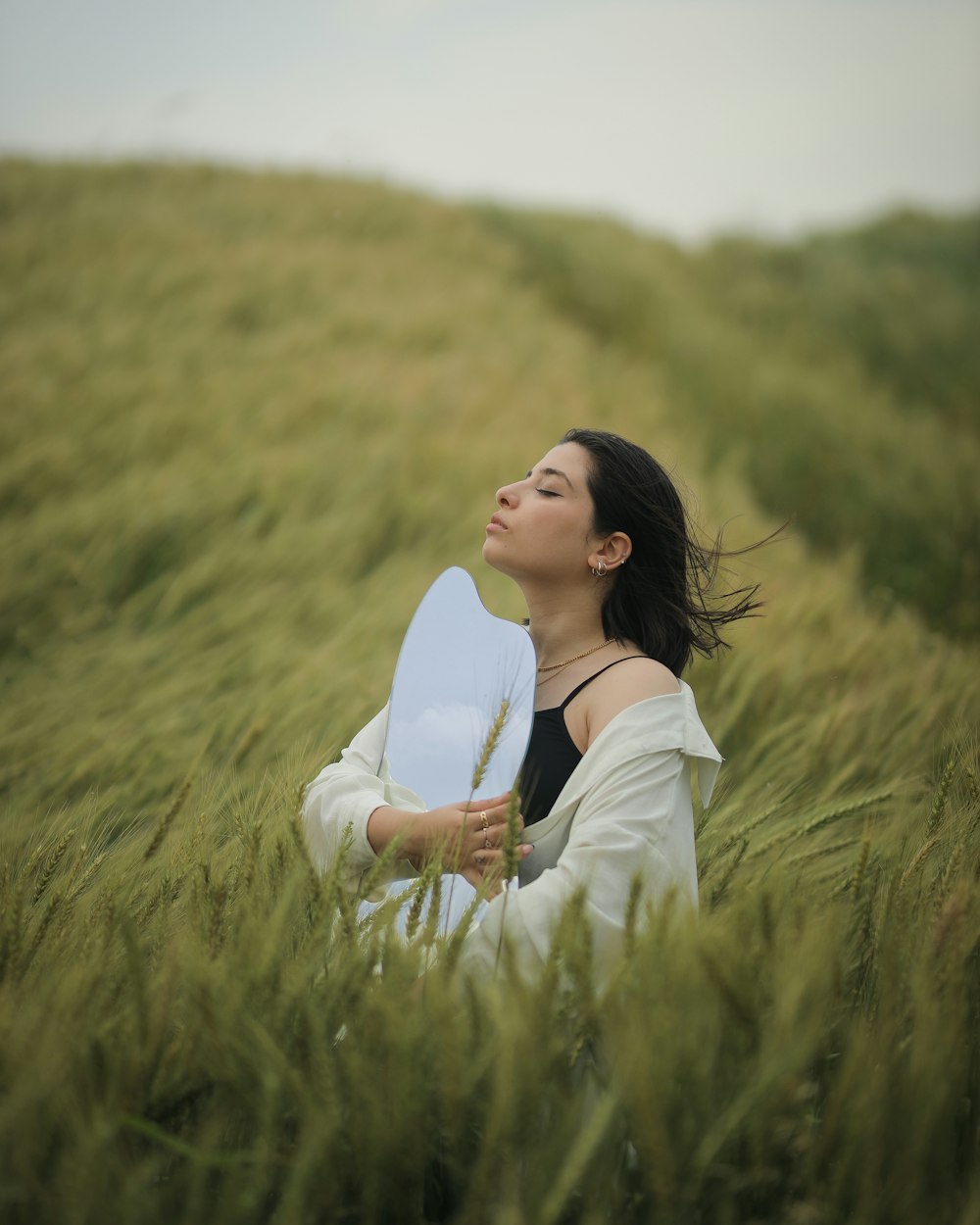 a woman sitting in a field holding a blue frisbee