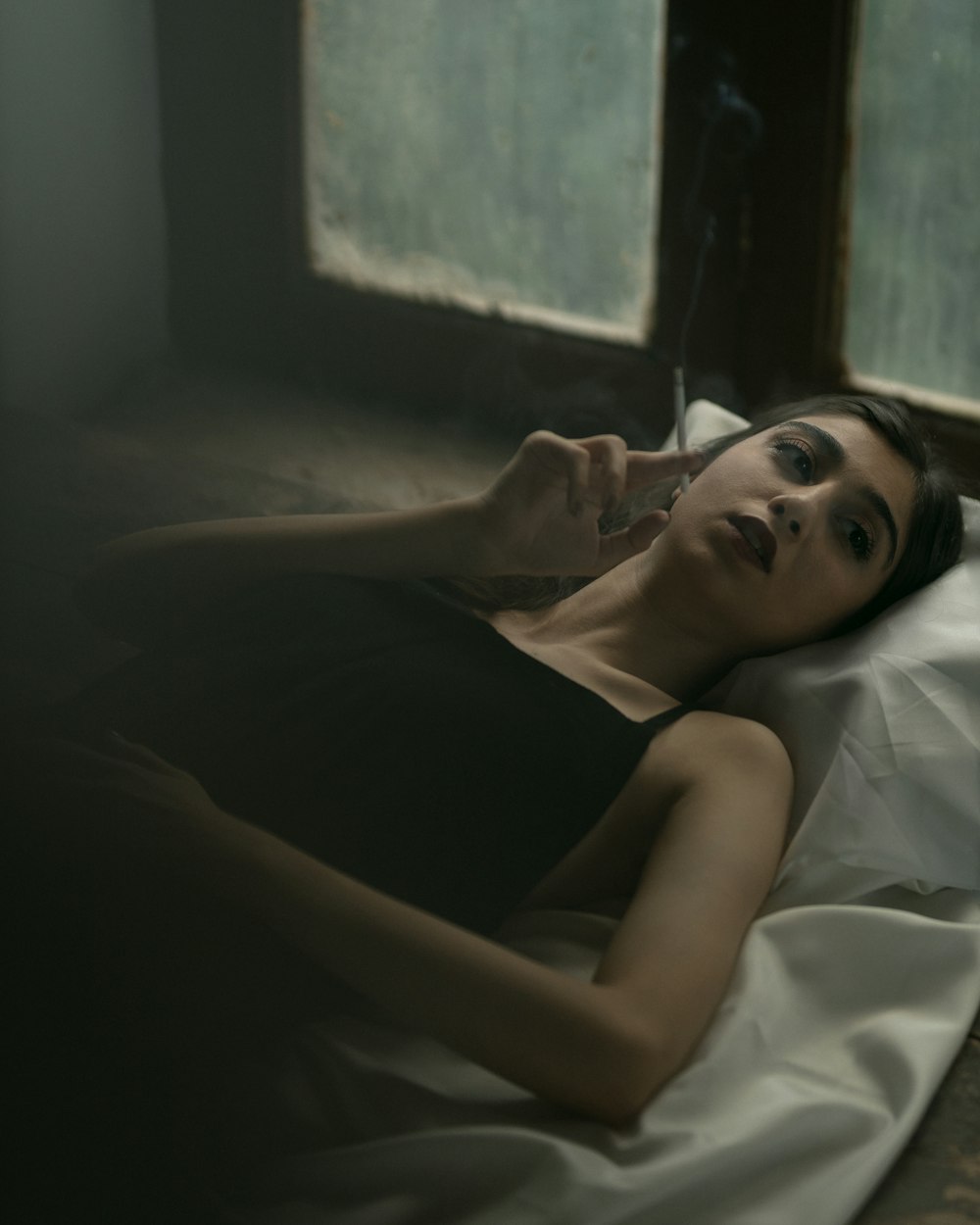 a woman laying on a bed smoking a cigarette