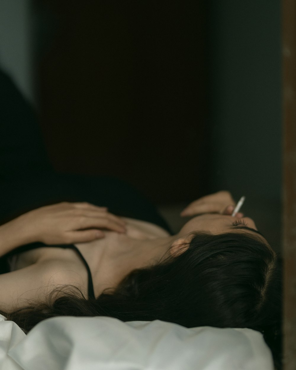 a woman laying on a bed with a cigarette in her mouth