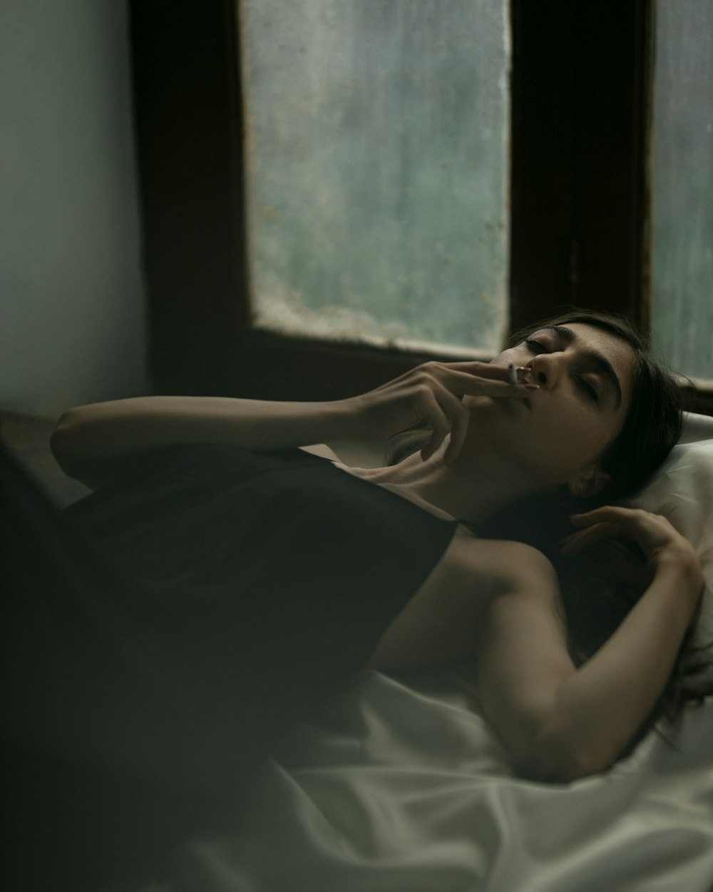 a woman laying on a bed with a white sheet