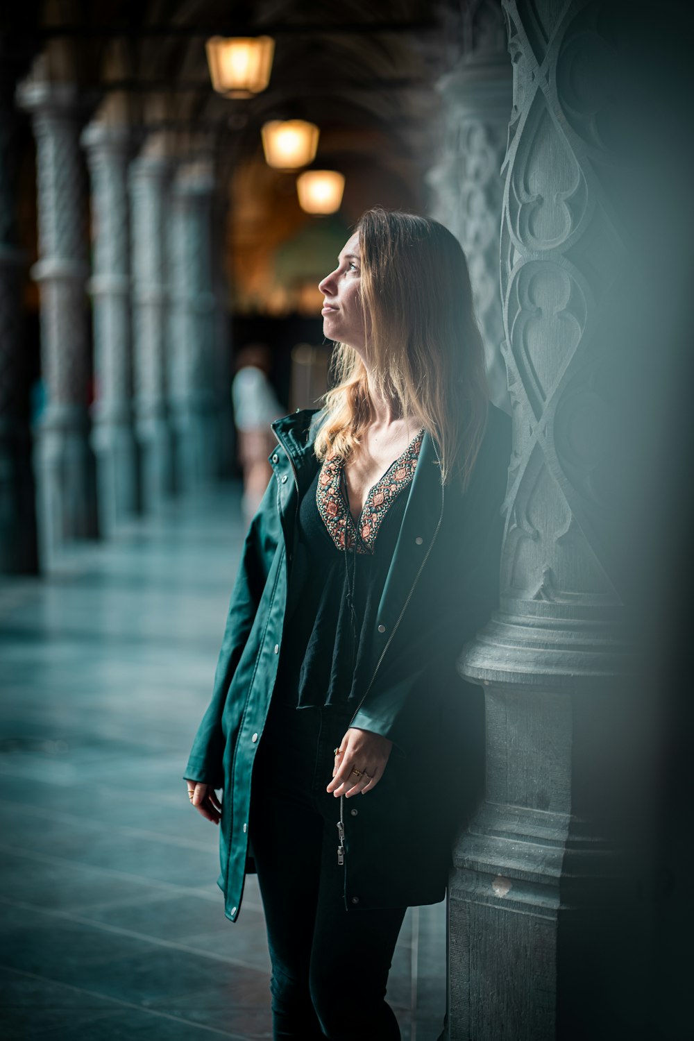 a woman standing next to a pillar in a building