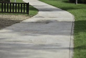 A textured concrete walkway winding through a landscaped yard with greenery on both sides