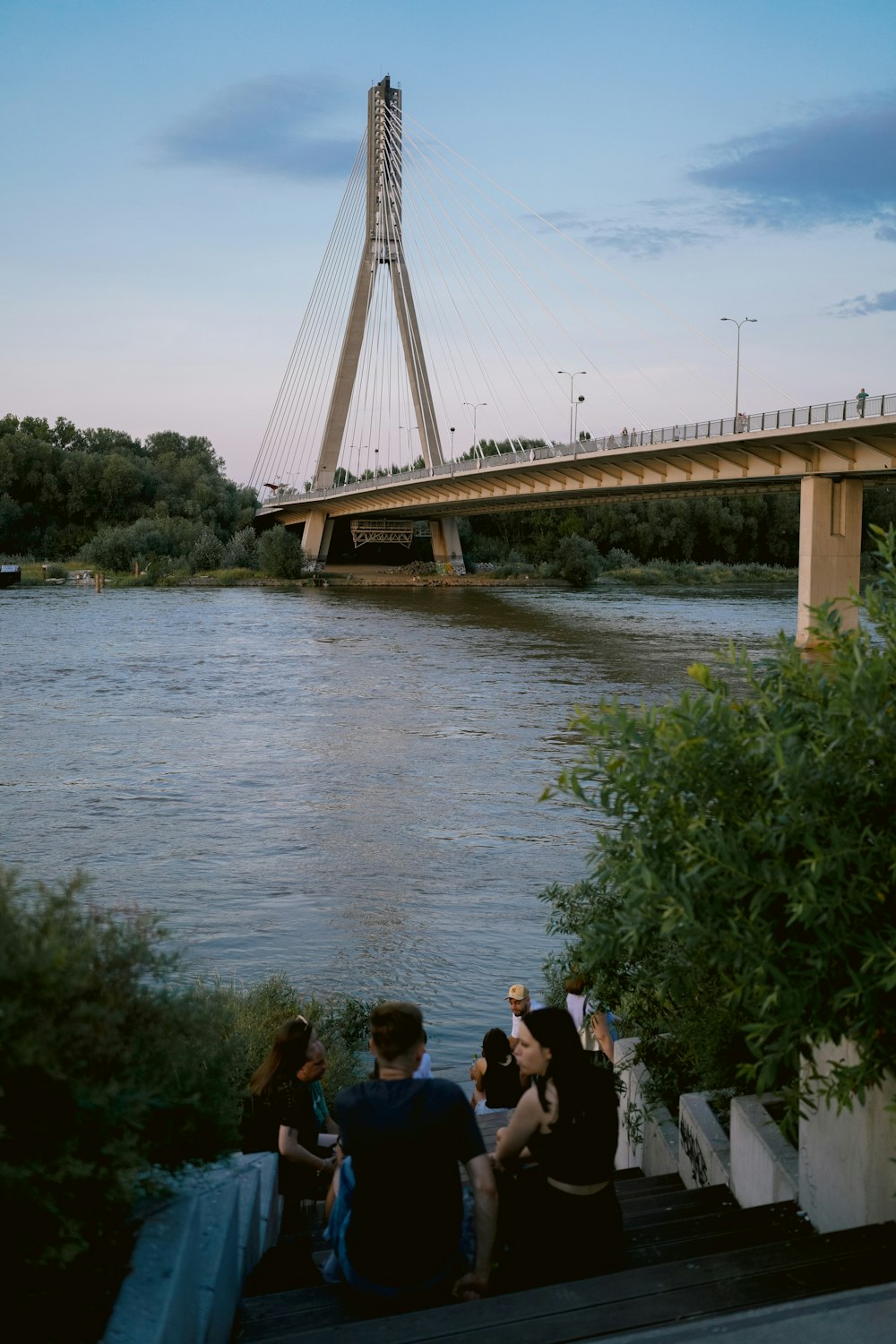 a group of people sitting on a dock next to a river