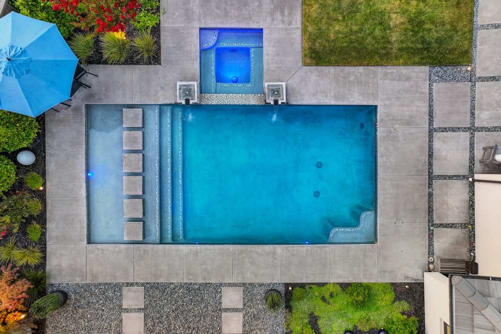 an aerial view of a swimming pool surrounded by greenery