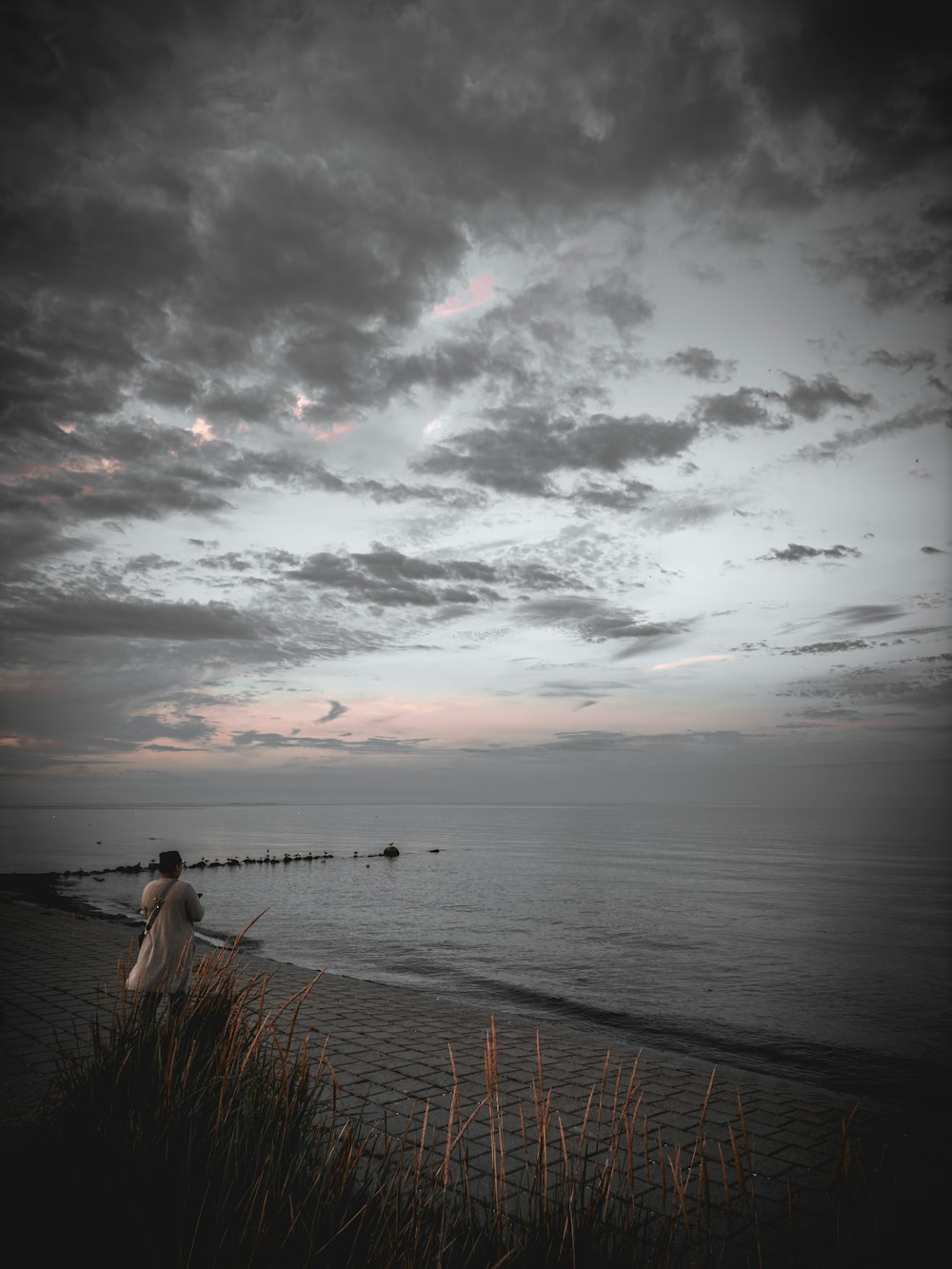 a man standing on top of a beach next to the ocean