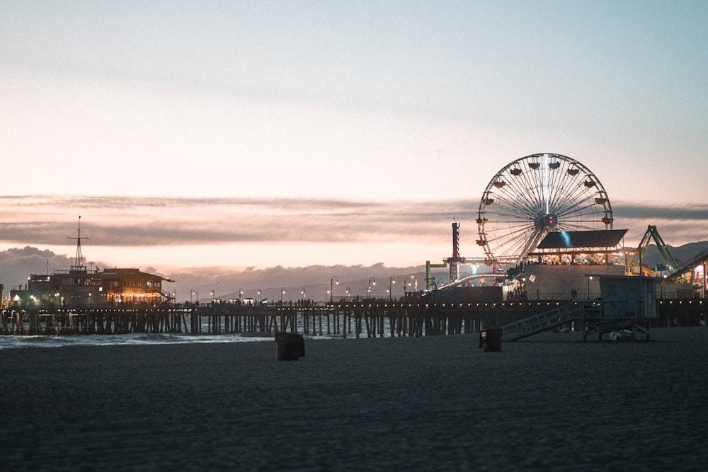 a ferris wheel sitting next to a pier at dusk