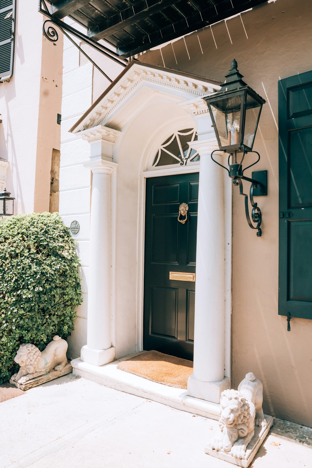 a black front door with a lamp on the side of it