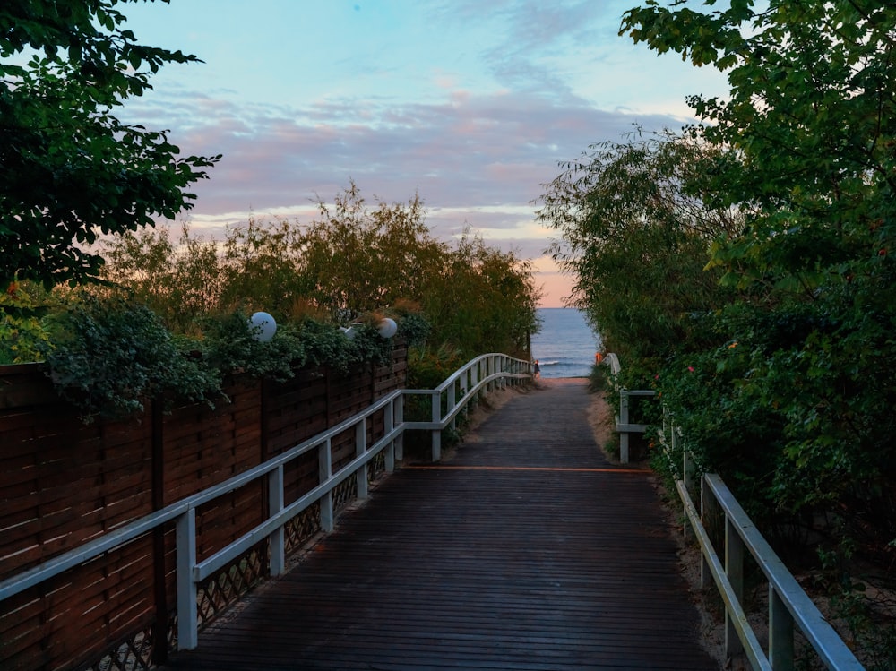 a wooden walkway leading to the beach at sunset