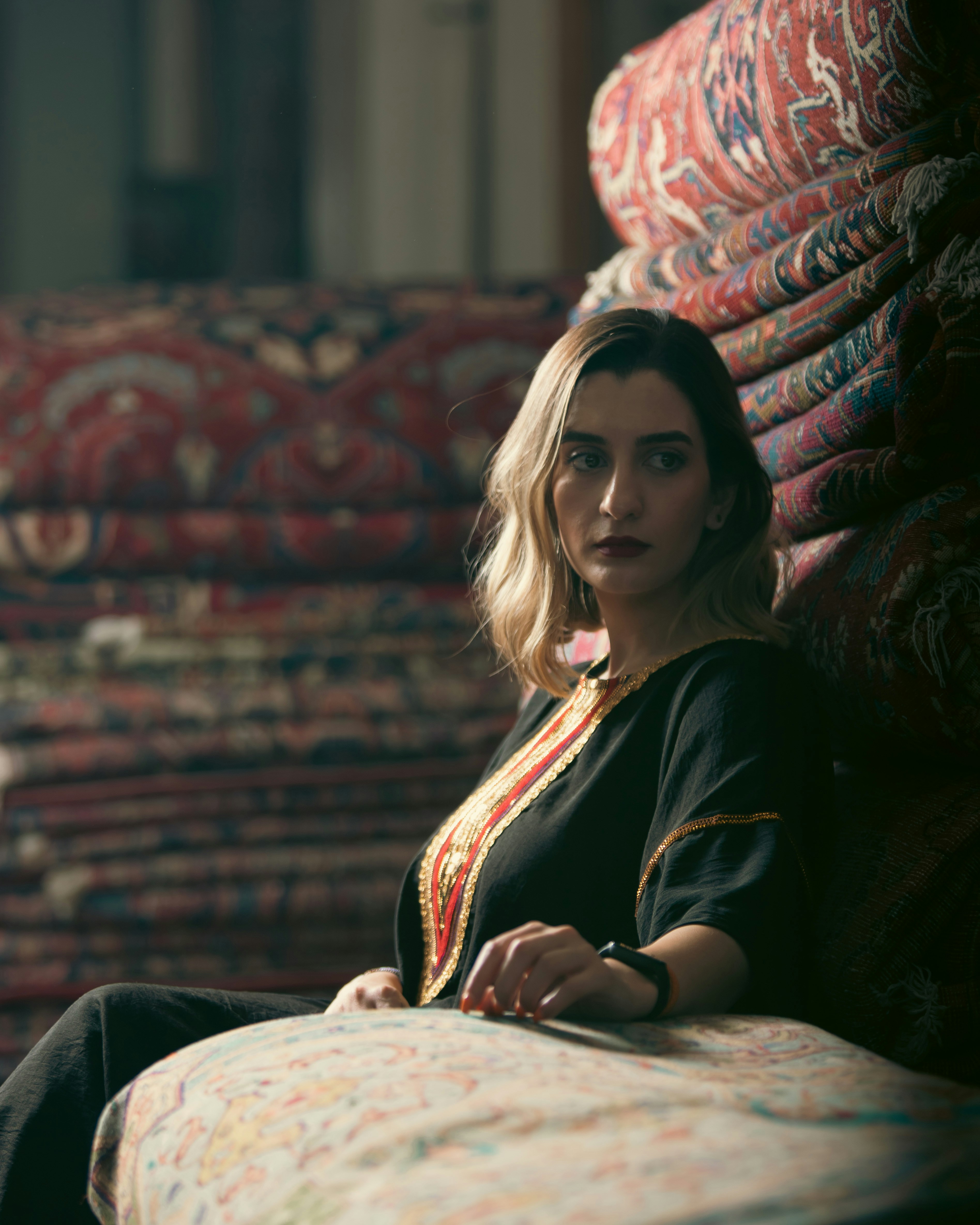 a woman sitting on top of a couch next to a pile of pillows