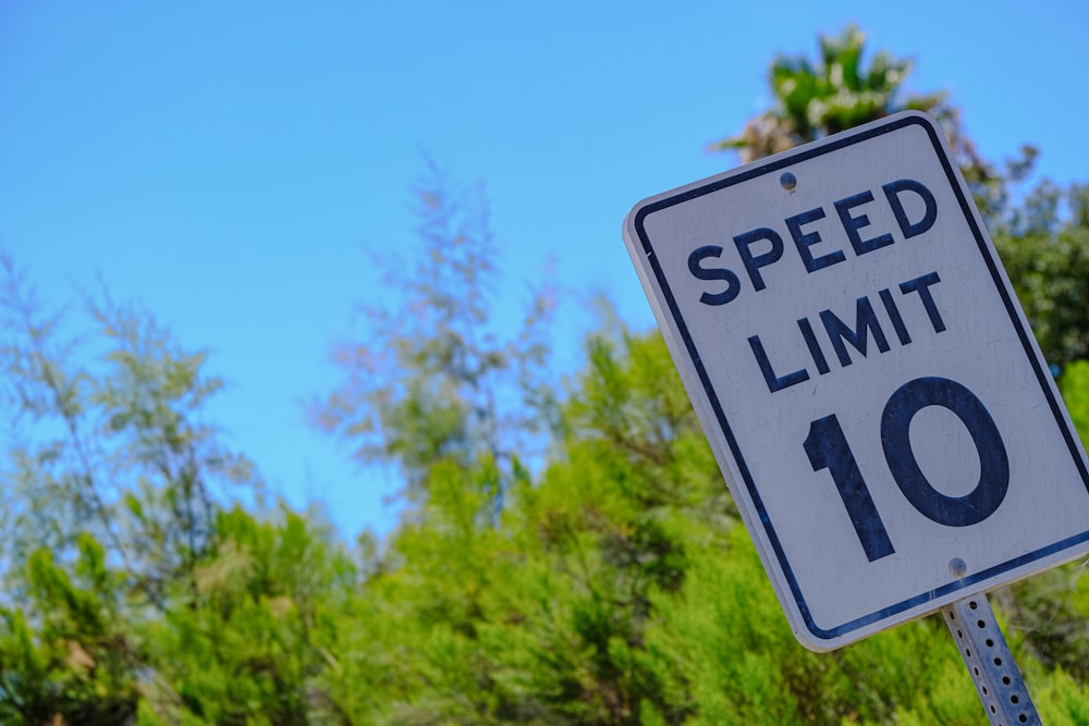 a speed limit sign with trees in the background