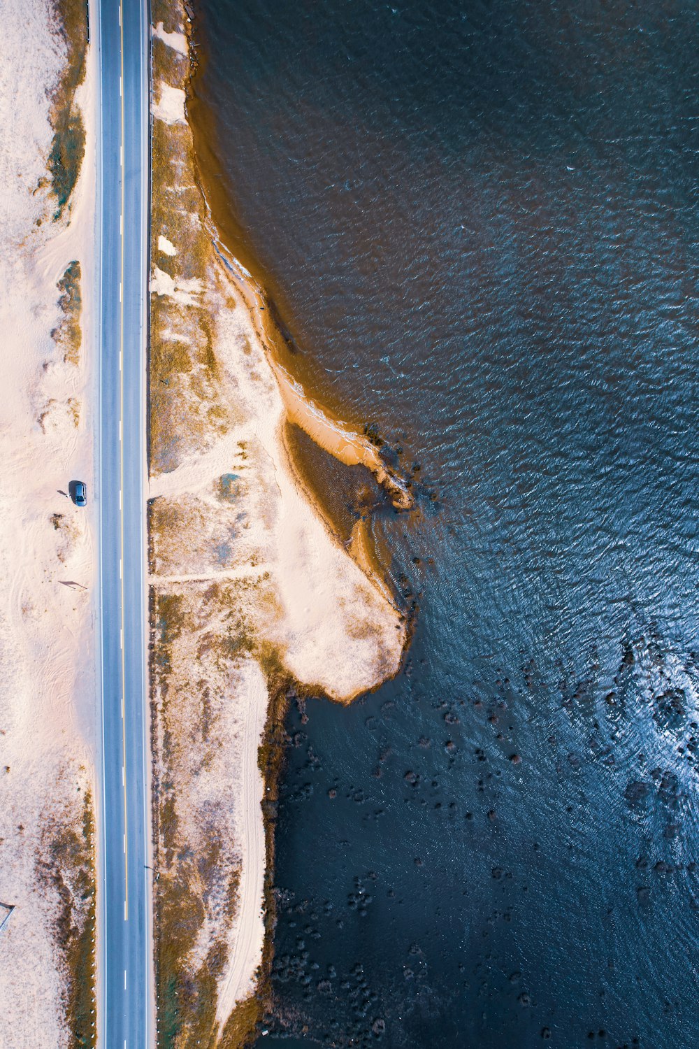 an aerial view of a road next to a body of water