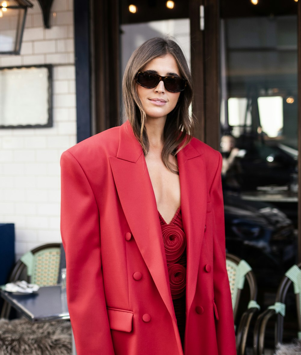 a woman wearing a red suit and sunglasses