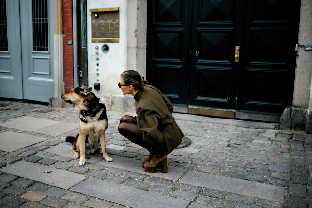 a woman kneeling down next to a dog