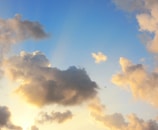 An airplane soaring above fluffy white clouds during golden hour.
