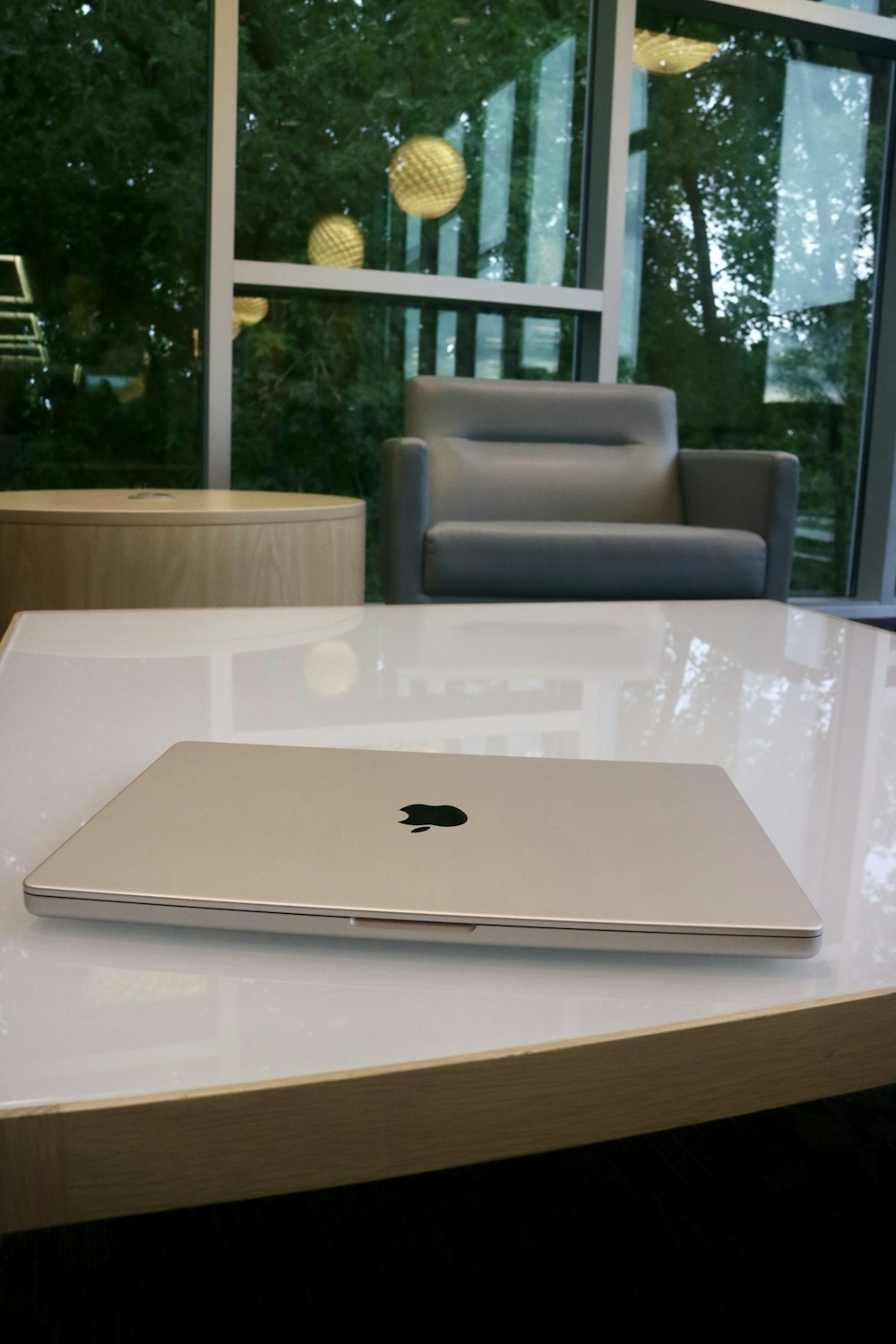 an apple laptop sitting on a table in front of a window