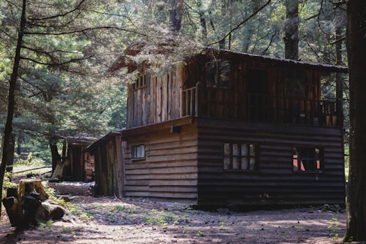 a wooden cabin in the woods with trees around it
