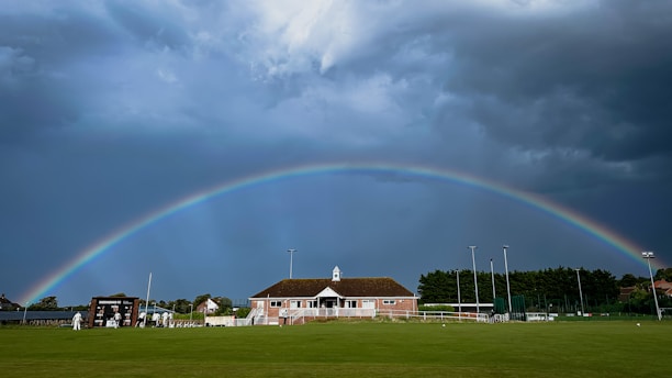 A vibrant softball flying over a rainbow-colored field under a clear blue sky.