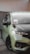 A sleek car with a modern design is parked on a tiled surface. The car features a shiny, light green exterior with a glossy black hood. It is equipped with stylish black wheels and a front grill with an integrated fog light. The windows are tinted, and there are decals on the windshield.