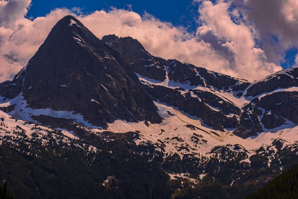 a mountain covered in snow under a cloudy sky