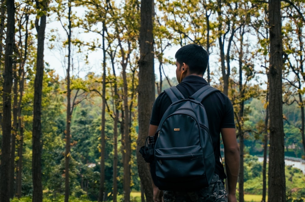 a man standing in the woods with a backpack