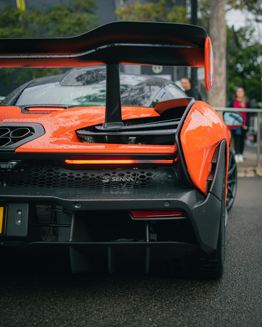 an orange sports car parked on the side of the road