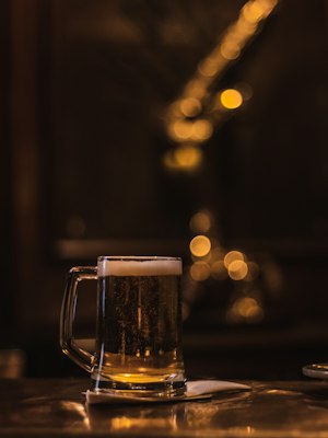 Vaso de cerveza solitario sobre una mesa en la oscuridad
