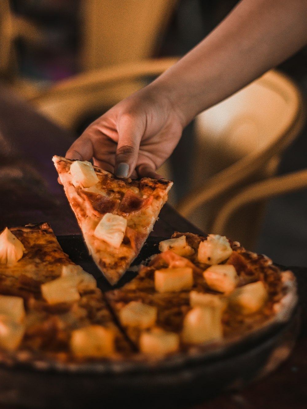 a person grabbing a slice of pizza from a pan