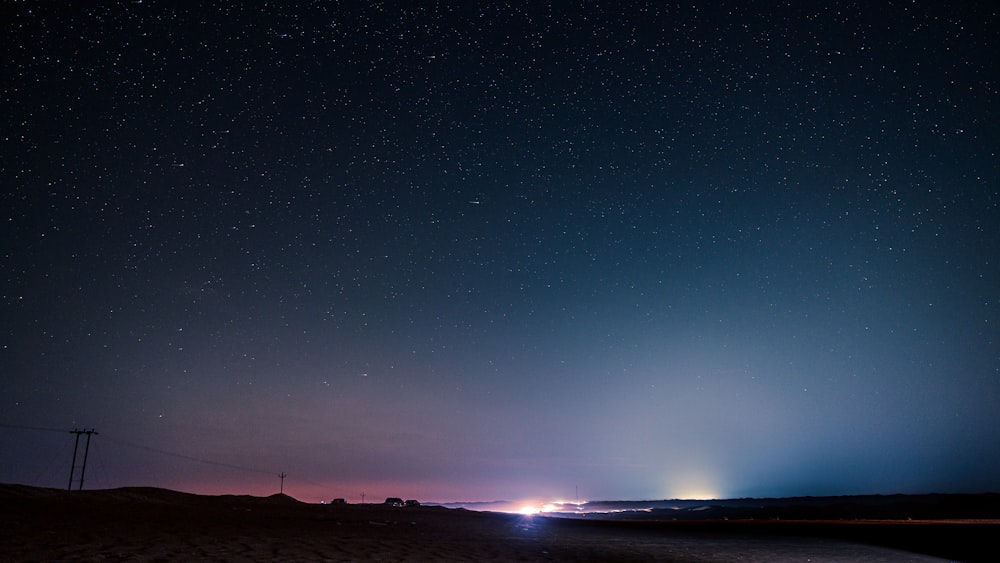 a night sky with stars and a car driving on the road