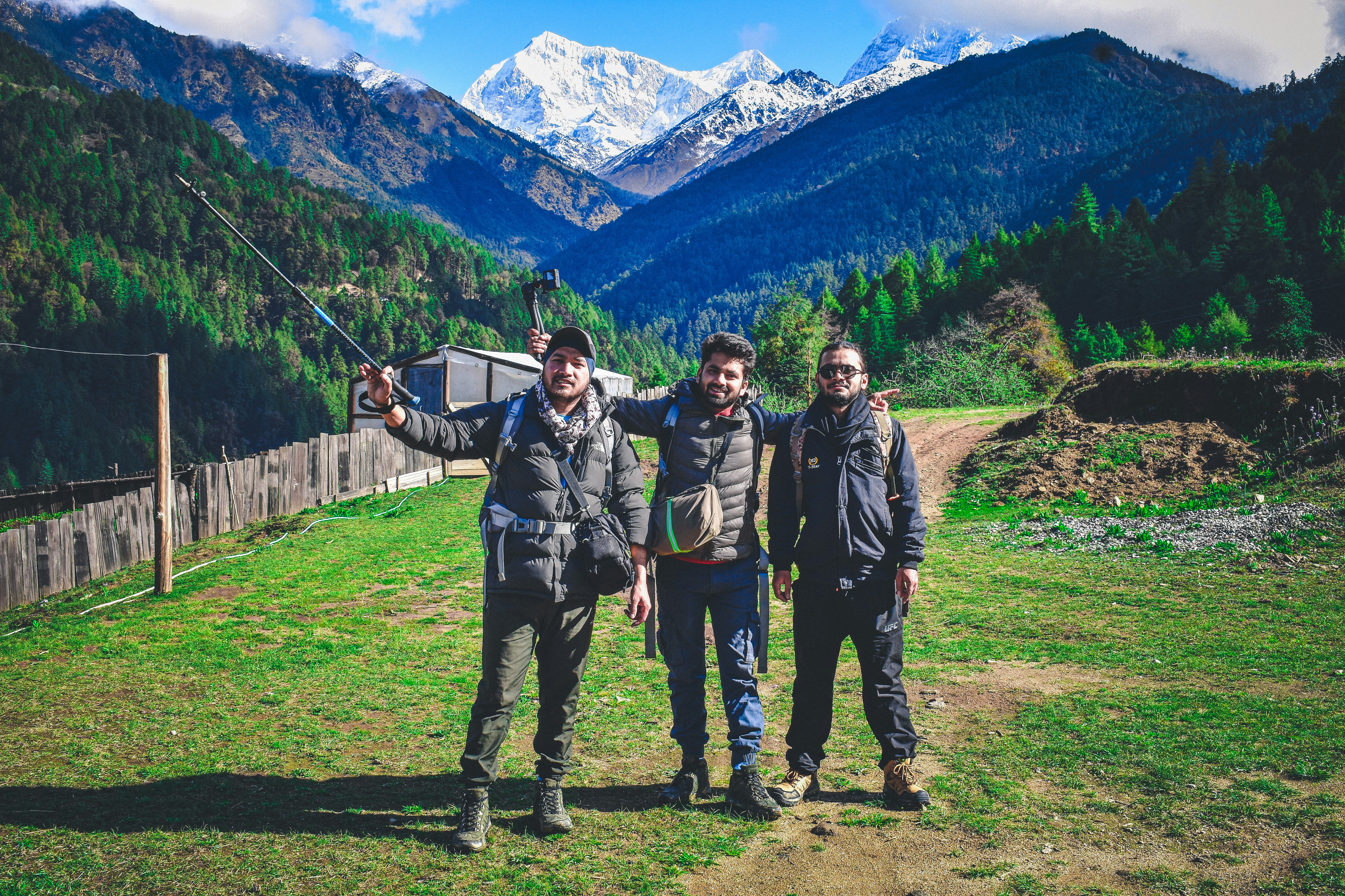 three people standing in a field with mountains in the background