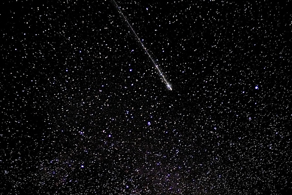 a dark sky with stars and a shooting star