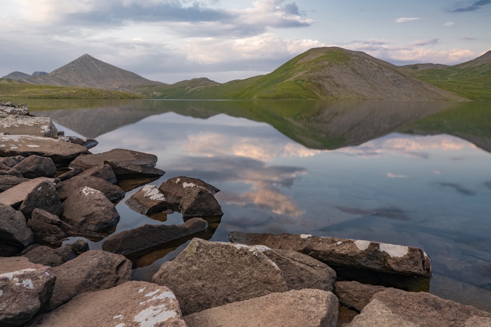 a lake surrounded by rocks with mountains in the background