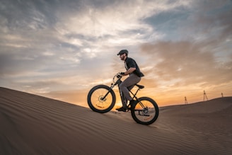 a man riding a bike on top of a sandy hill