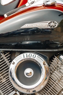 A close-up view of a motorcycle engine, specifically highlighting the Drag Star branding on the black metal surface. The engine features polished chrome components, including a circular emblem with the number 1100 on it.