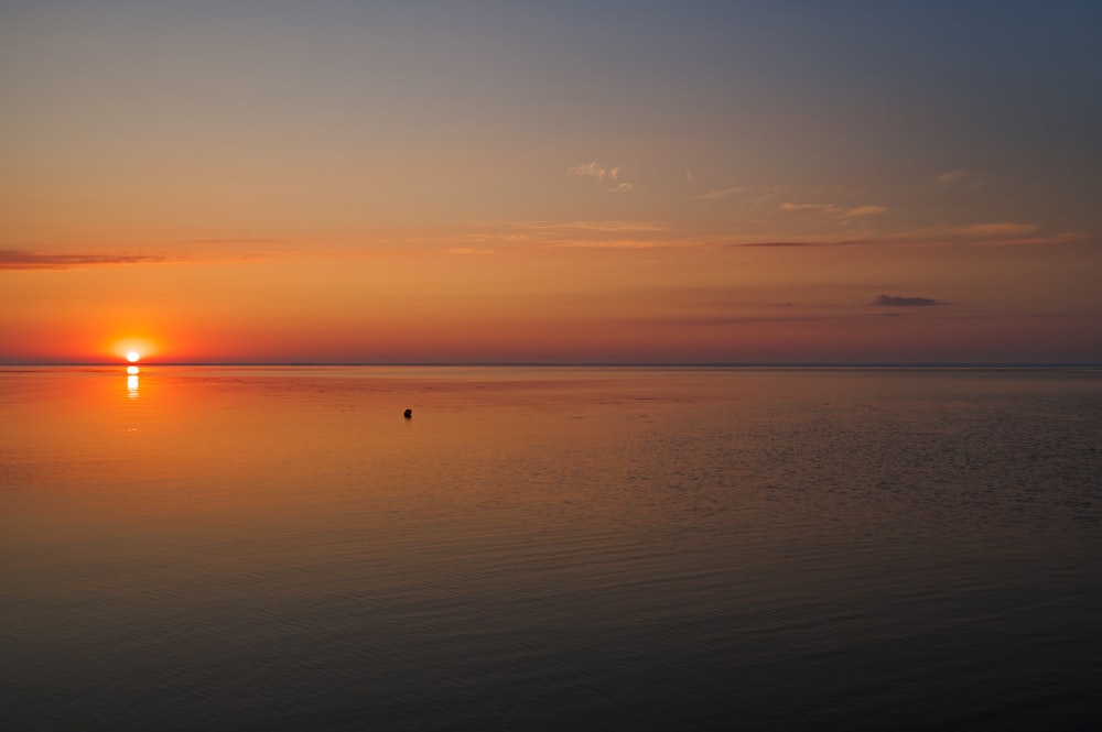 a large body of water with a sunset in the background