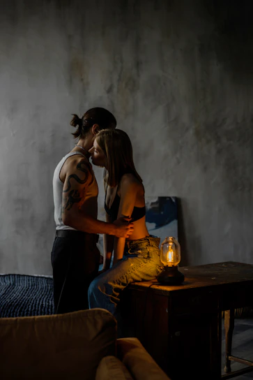 A cozy, dimly lit room with two silhouettes leaning close, sharing a secret smile.