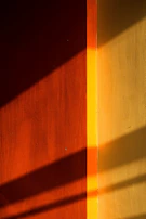 Dynamic angle capturing the interplay of orange industrial accents on the bag against warm sand-colored concrete
