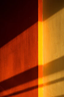 Dynamic angle capturing the interplay of orange industrial accents on the bag against warm sand-colored concrete