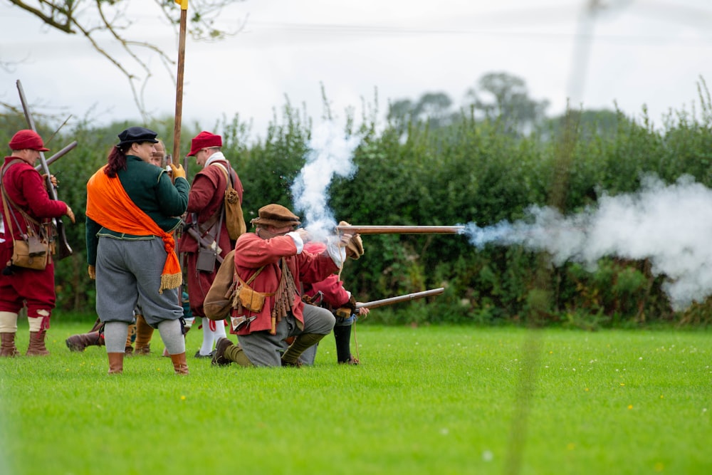 a group of men in red and grey uniforms with guns