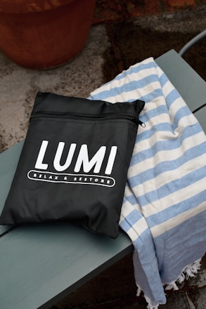 A sleek, elegant wellness bag resting on a bamboo mat with tropical flowers around it.