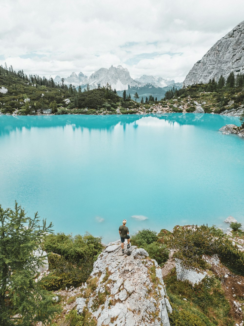 a person sitting on a rock near a lake