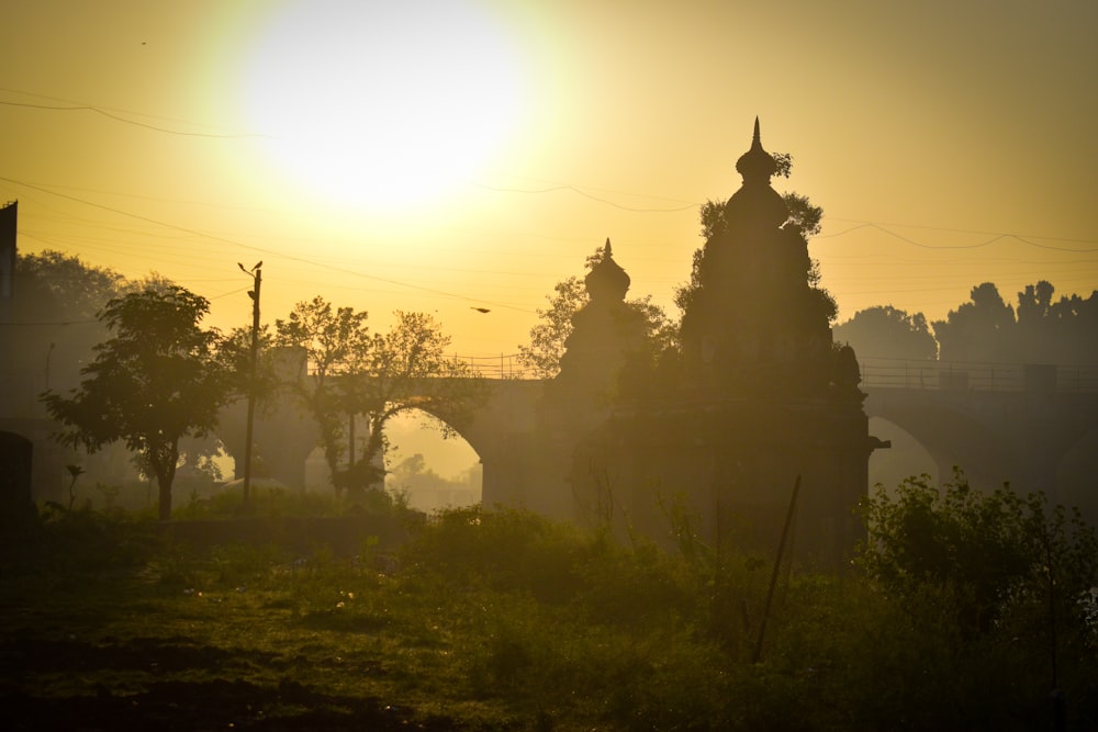 the sun is setting over a bridge with a clock tower