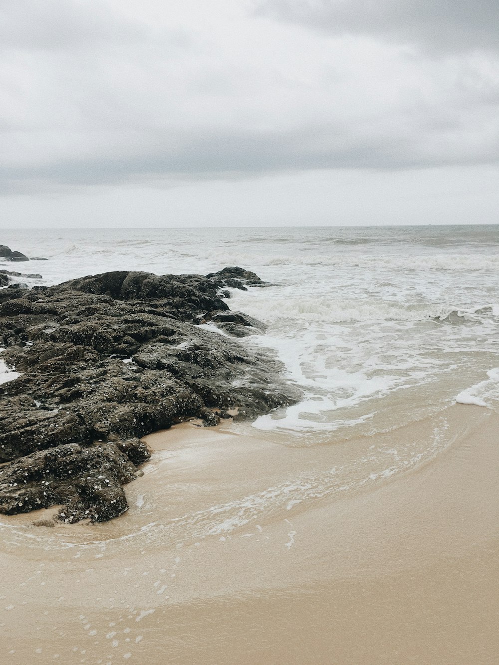 a sandy beach next to the ocean under a cloudy sky