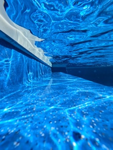 A sleek robotic pool cleaner gliding smoothly underwater in a sparkling blue pool.