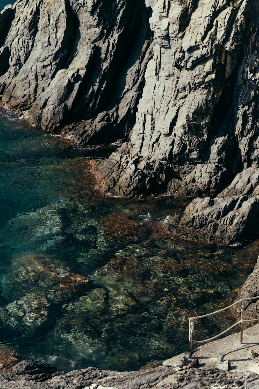 a rocky cliff with a body of water next to it