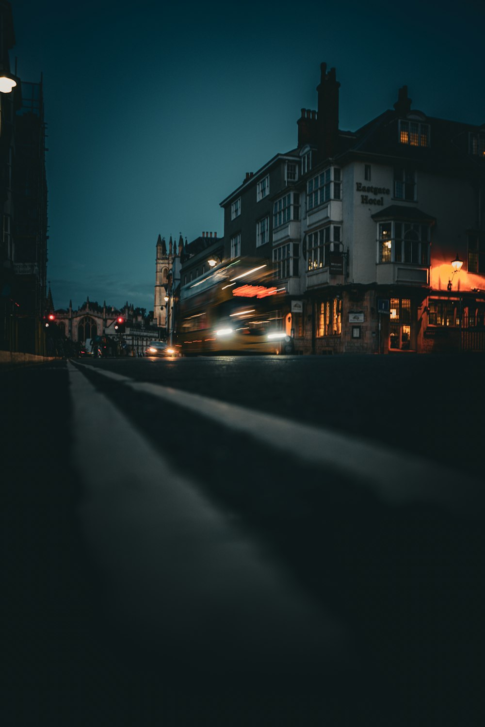 a city street at night with a double decker bus passing by