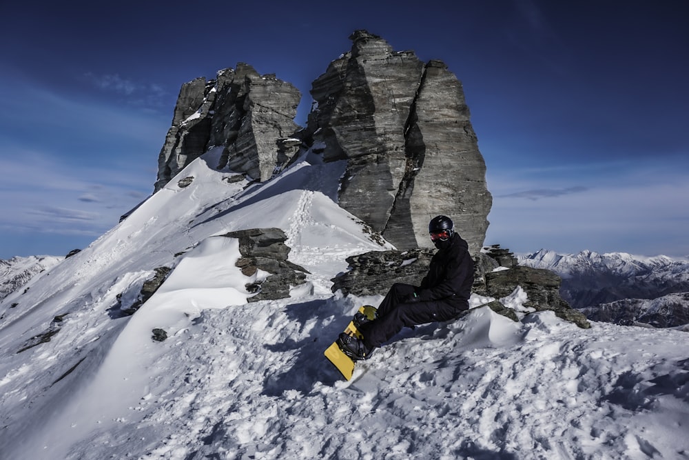 a snowboarder is sitting on a snowy mountain
