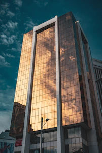 A sleek, modern architectural building bathed in warm golden light against a deep navy twilight sky.