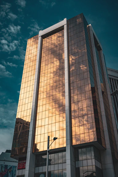 A sleek, modern architectural building bathed in warm golden light against a deep navy twilight sky.
